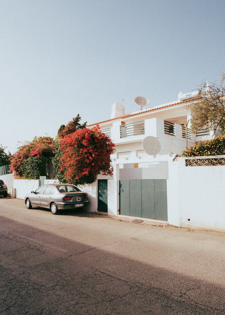 Discover a serene white villa on a sunny street in Albufeira, Portugal, surrounded by vibrant bougainvillea.