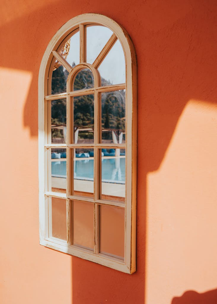Reflection of tranquil pool in rustic arched window on a sunny day in Corfu, Greece.